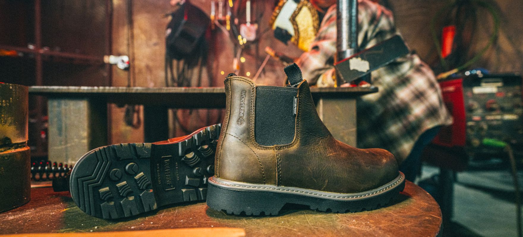 Work boots with a workshop in the background.