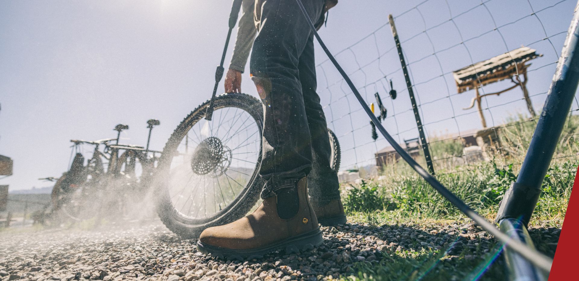 a man power-washing a bicycle wheel.